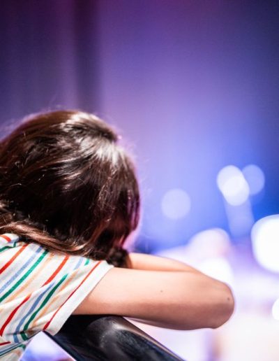 a young girl looks at a stage from a theatre box photographed by surrey social stock photography