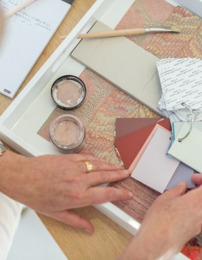 a woman looks at samples in her interior design studio during a personal brand photography shoot in guildford