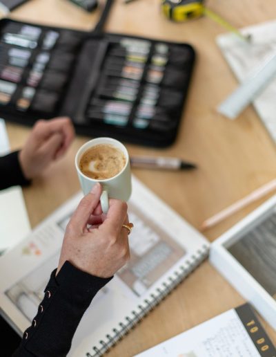 a woman holding a cup of coffee at her desk during a personal brand photography shoot in surrey