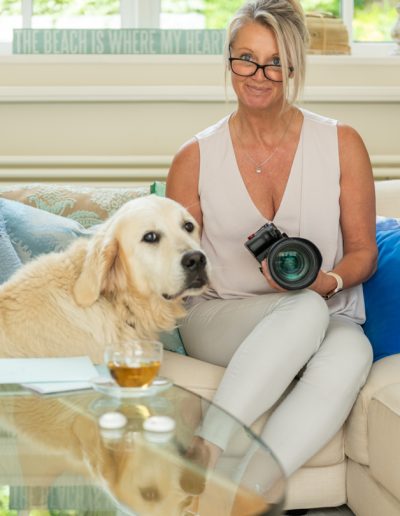 a woman sits in a sun filled room with her camera during a personal branding photography shoot in guildford