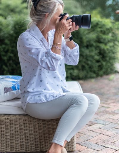 a woman takes a photography whilst seated on garden furniture during a personal branding photography shoot in surrey