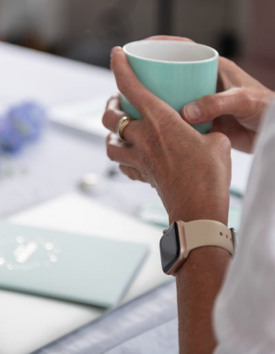 a woman holding a cup of coffee at her desk during a personal brand photography shoot in surrey