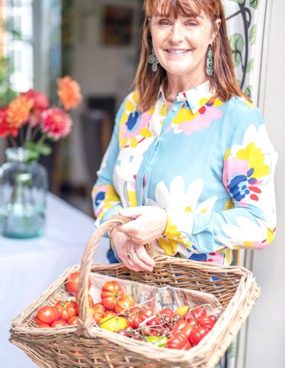a woman holding a basket of fresh tomatoes during a personal brand photography shoot in surrey
