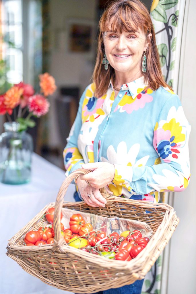 a woman holding a basket of fresh tomatoes during a personal brand photography shoot in surrey