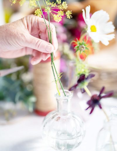 a young woman arranges flowers into a bud vase during a personal brand photography shoot in guildford