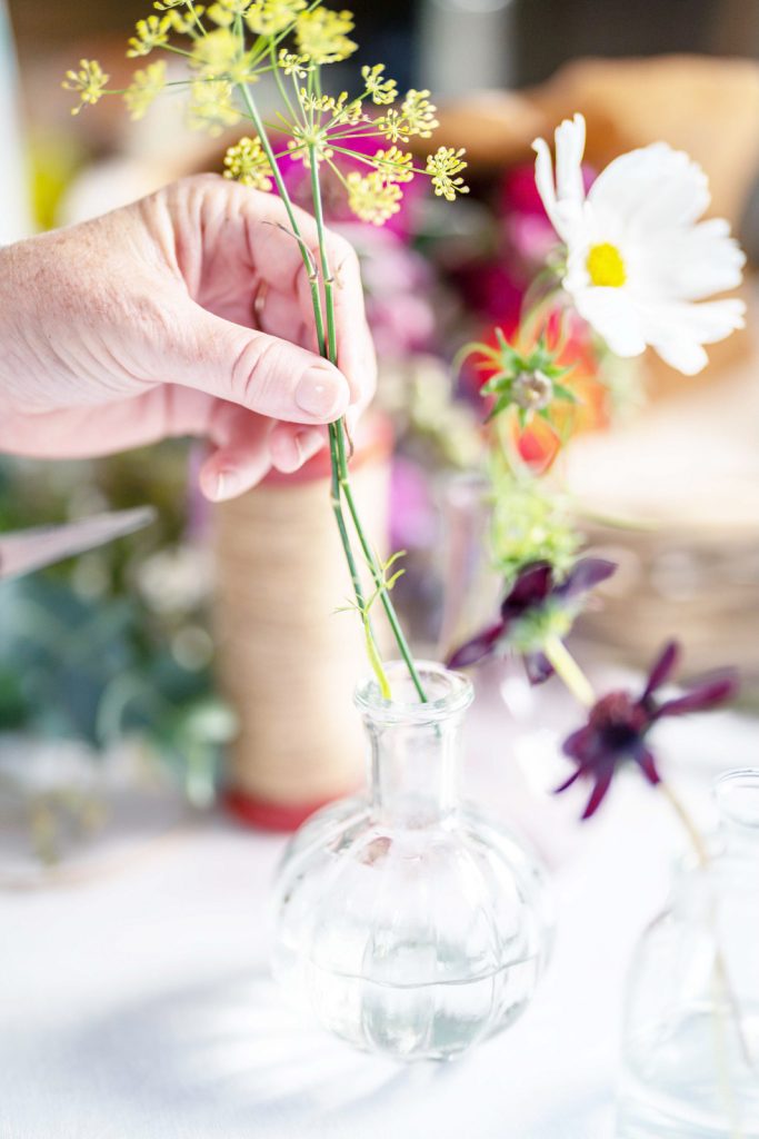a young woman arranges flowers into a bud vase during a personal brand photography shoot in guildford