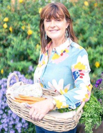 a young woman holding a basket of vegetables from her garden during a personal brand photography shoot in guildford