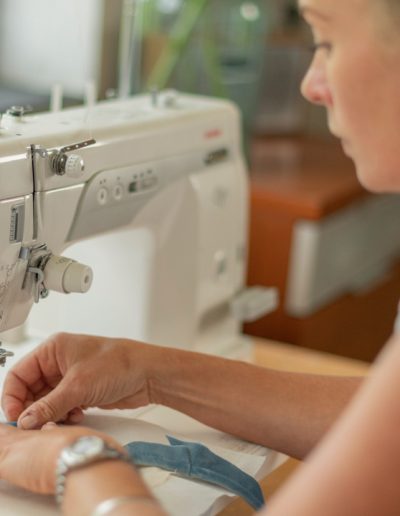 a young woman works at a sewing machine during a personal brand photography shoot in guildford