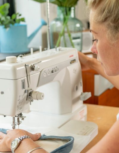 a young woman works at a sewing machine during a personal brand photography shoot in guildford