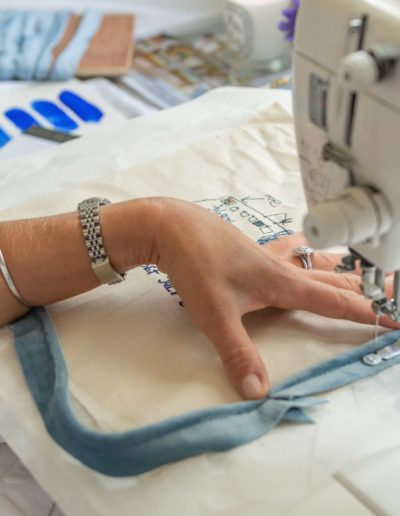 a young woman works at a sewing machine during a personal brand photography shoot in guildford