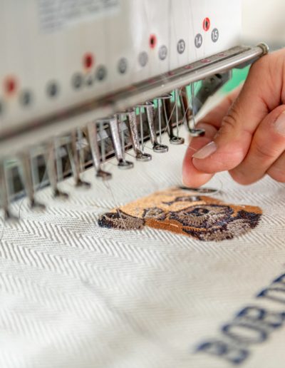 a young woman works at a sewing machine during a personal brand photography shoot in guildford