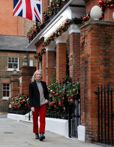 a young woman stands outside a london townhouse at christmas during a personal brand photography shoot