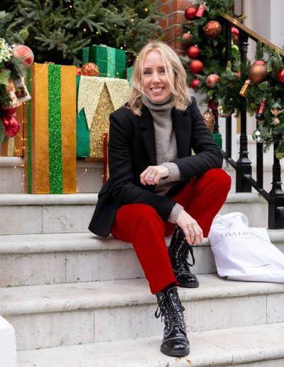 a young woman sits outside a london townhouse at christmas time during a personal brand photography shoot