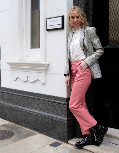 a young woman stands at the entrance to her skincare clinic during a personal brand photography shoot in london