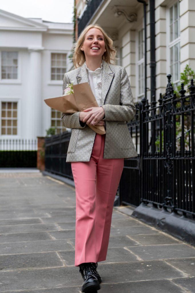 a young woman strolls down a london street holding a bunch of flowers during a personal brand photography shoot