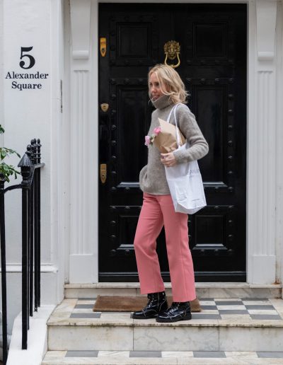 a young woman stands outside a london townhouse holding flowers during a personal bran photography shoot