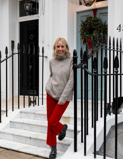 a young woman stands outside a london townhouse at christmas during a personal brand photography shoot