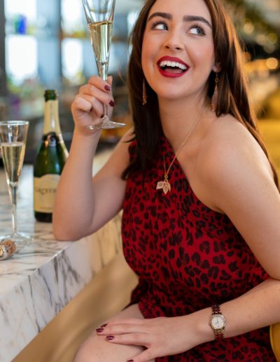 a young woman poses at a bar with a cocktail for a lifestyle photography shoot in guildford
