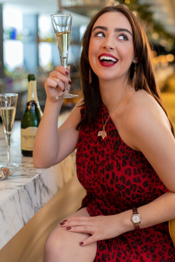 a young woman poses at a bar with a cocktail for a lifestyle photography shoot in guildford