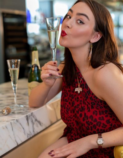 a young woman poses at a bar with a cocktail for a lifestyle photography shoot in guildford