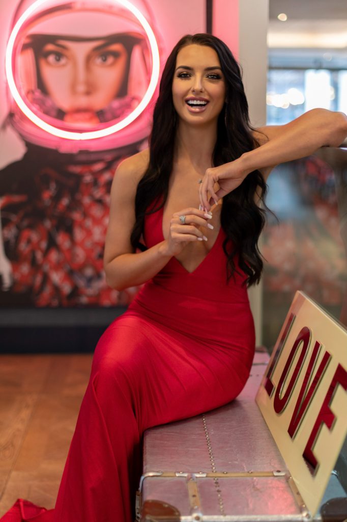 a young woman in a glamorous red dress poses at a restaurant for a lifestyle photography shoot in guildford