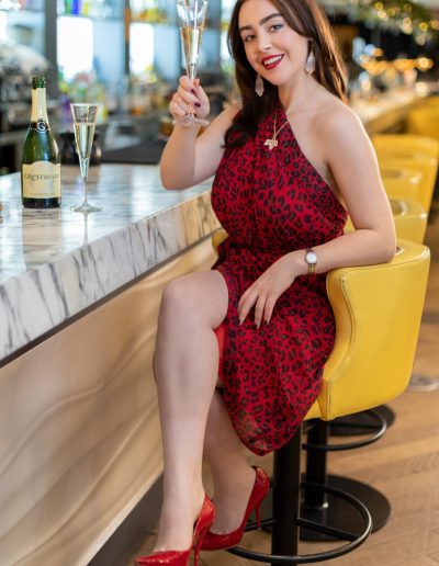 a young woman poses at a bar with a cocktail for a lifestyle photography shoot in guildford