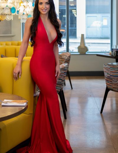 a young woman in a glamorous red dress poses at a restaurant for a lifestyle photography shoot in guildford