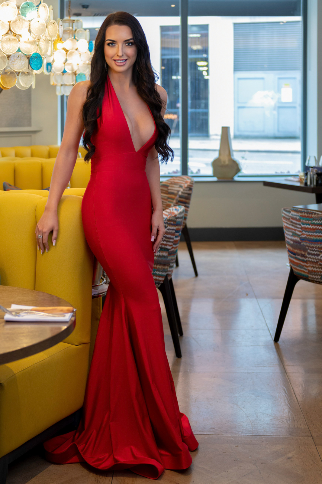 glamorous young woman sitting in a bar wearing a red dress during a photography shoot in guildford