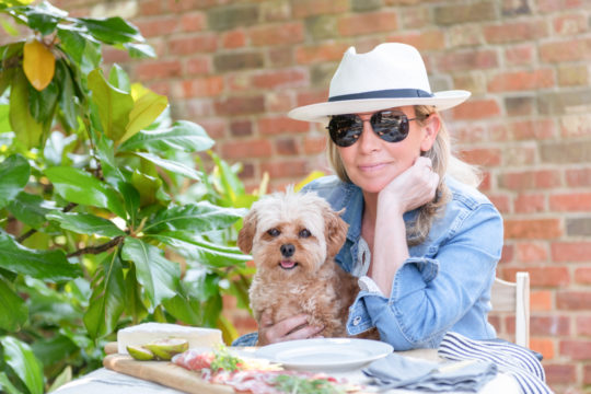 woman sits with her cute puppy at an al fresco lunch table