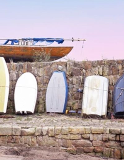 a row of rowing boats agains a harbour wall during a travel photography shoot in scotland