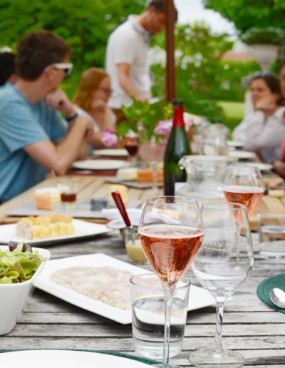 a group of people sit around a summer al fresco meal on their table in france