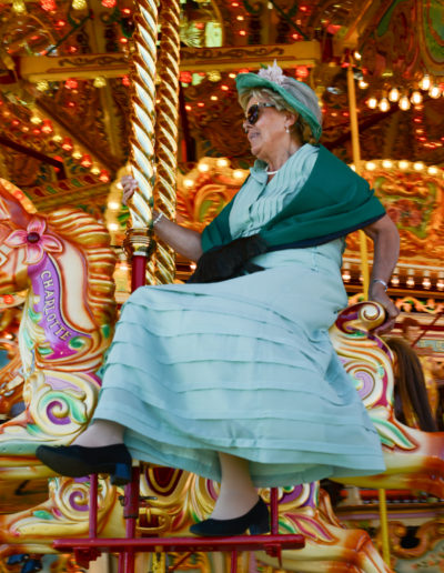 a lady sits on a carousel horse at goodwood revival