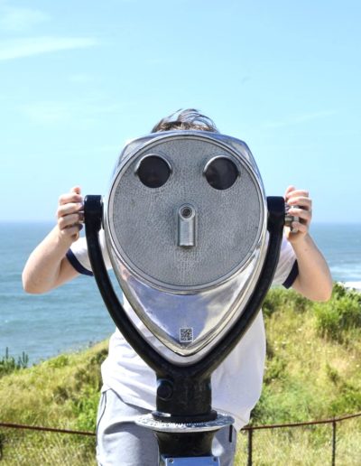 a small boy looks through a viewfinder in montauk