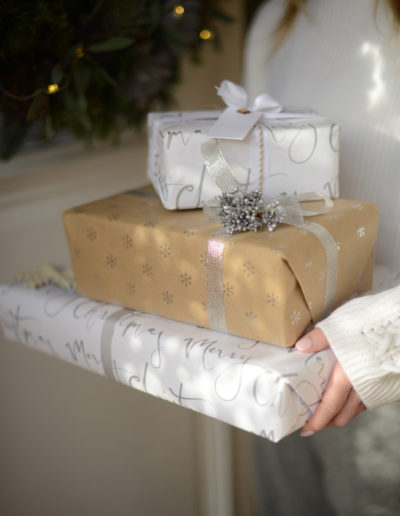 a woman holds a pile of wrapped christmas presents during a lifestyle photography shoot in guildford