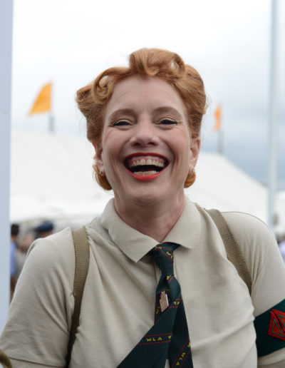a woman in vintage clothes laughs at goodwood revival