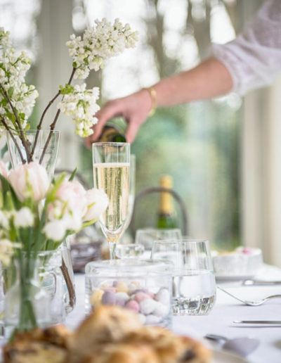 a woman pours a glass of champagne at an easter table setting