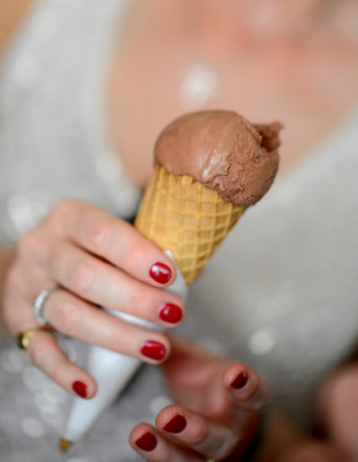 woman with red nails holding a chocolate ice cream cone