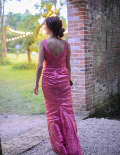 a woman in a ball gown walks through the door of a walled garden at grange park opera in surrey