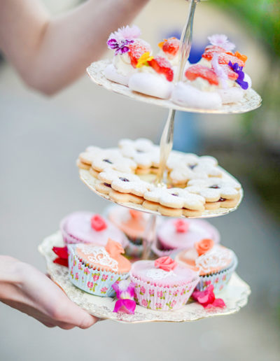 a waitress holds a cake stand filled with cakes during a lifestyle photography shoot in surrey