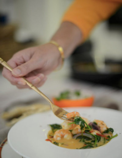 a woman puts a fork into bowl of food