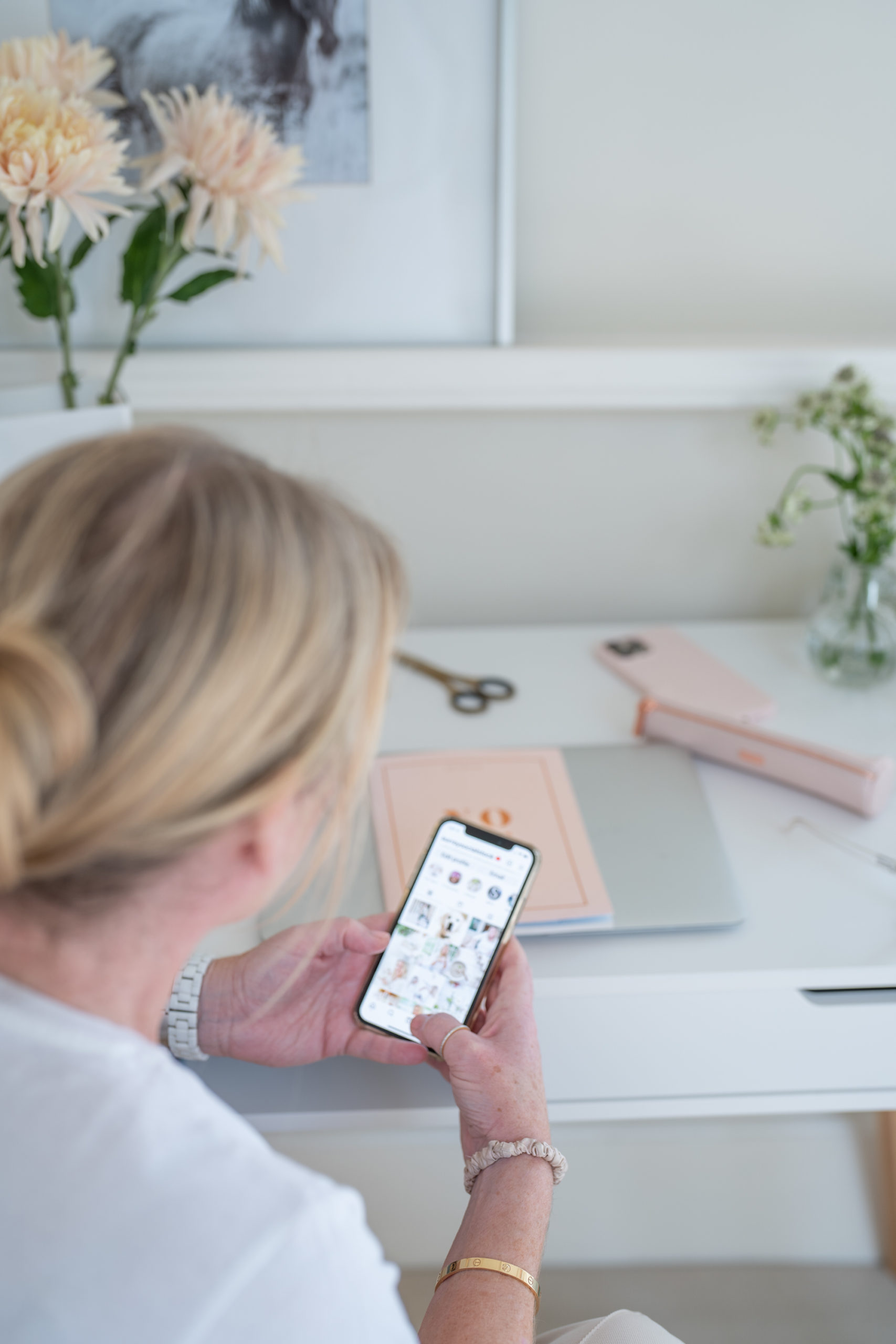 a woman checks her instagram feed at her home office desk photographed by business photographers surrey social stock photography.