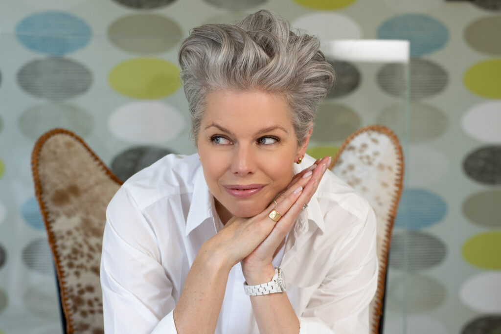 a woman sits on a cowhide chair during a personal brand photography shoot in guildford