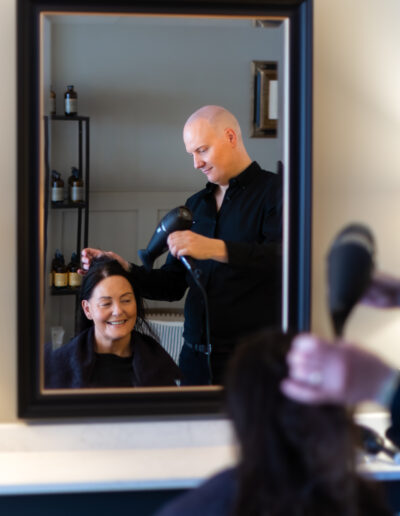 a hair dresser blow dries a client's hair during a personal brand photography shoot