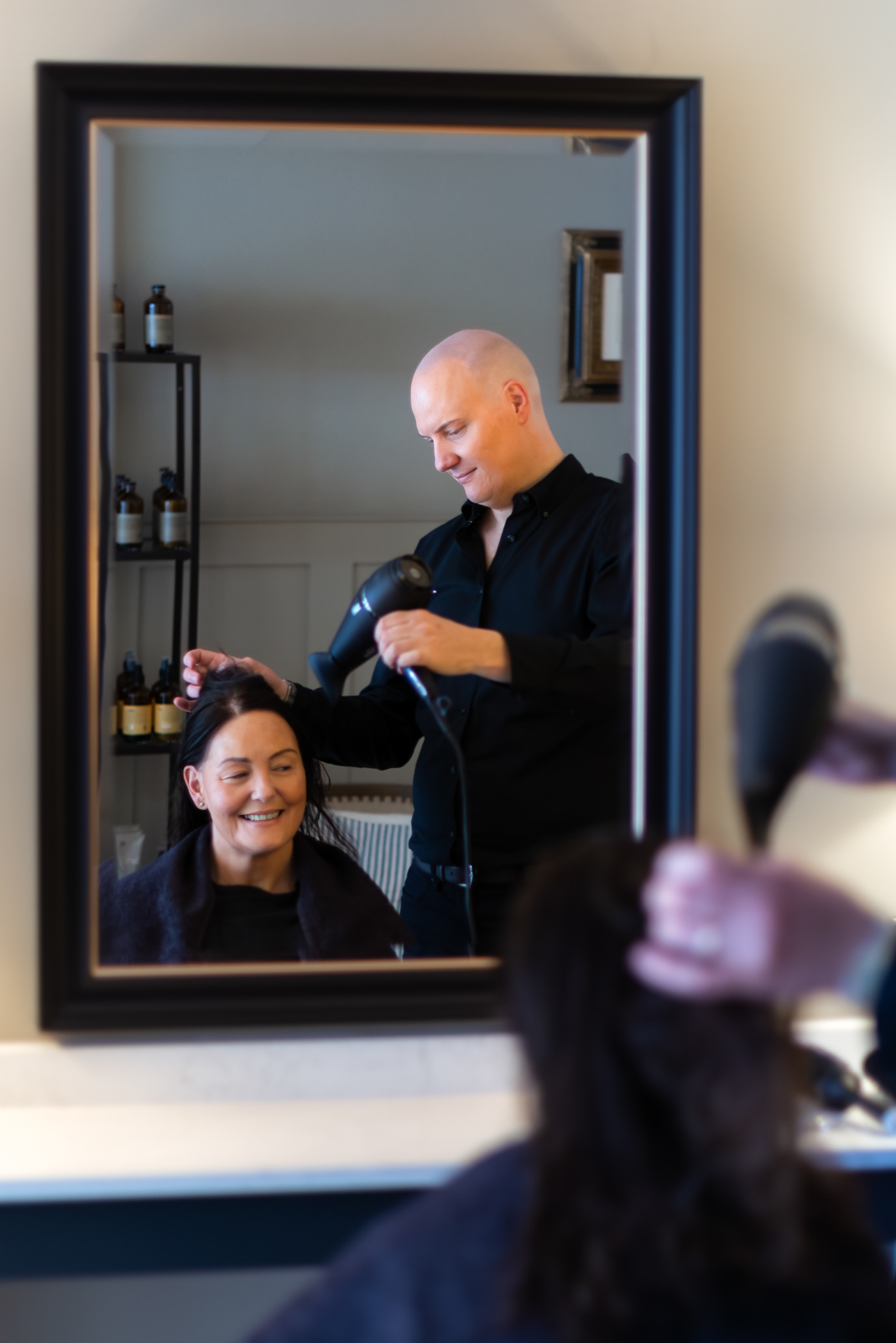 a hair dresser blow dries a client's hair during a personal brand photography shoot