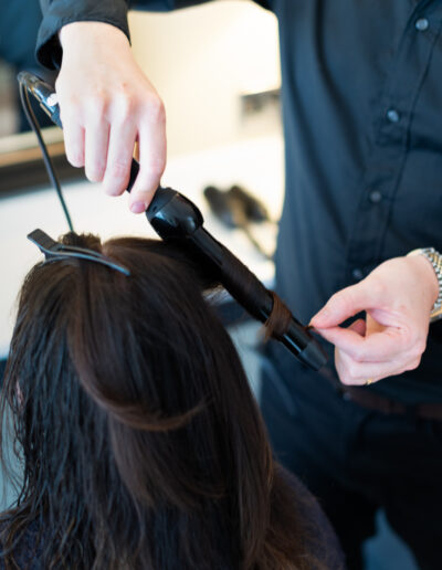 a hair dresser curls a client's hair during a personal brand photo shoot