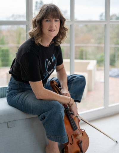 a woman sits on a bench with her violin