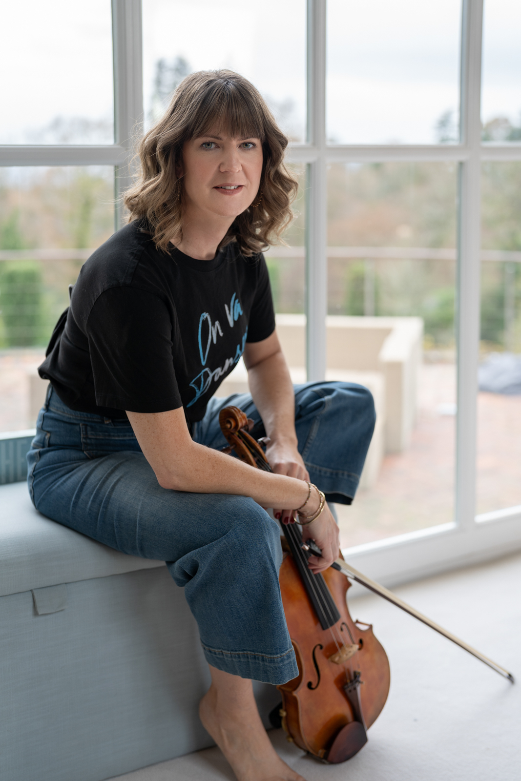 a woman sits on a bench with her violin