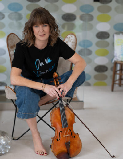 a woman sits on a chair with her violin