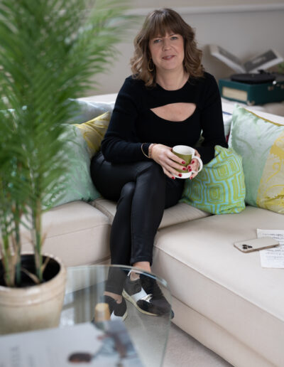 a woman sitting on a sofa smiles for a portrait