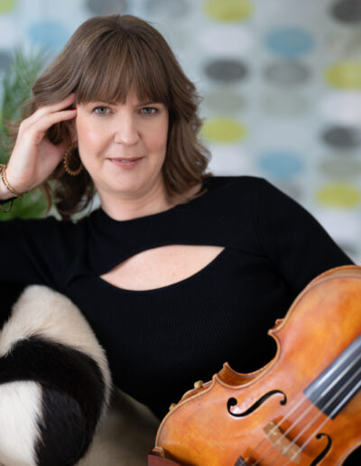 a violinist reclines on a sofa with her violin